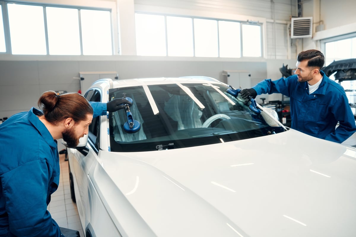 Professional auto glass technician installing windshield